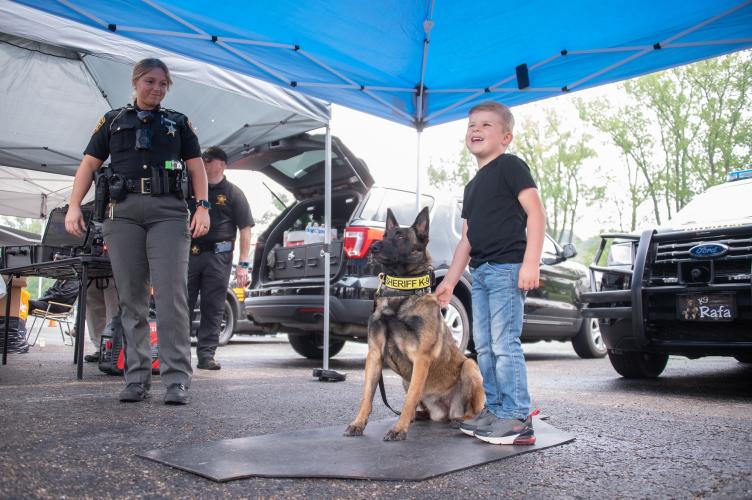 A child stands next to a police dog and a law enforcement officer at 儿童与警察节