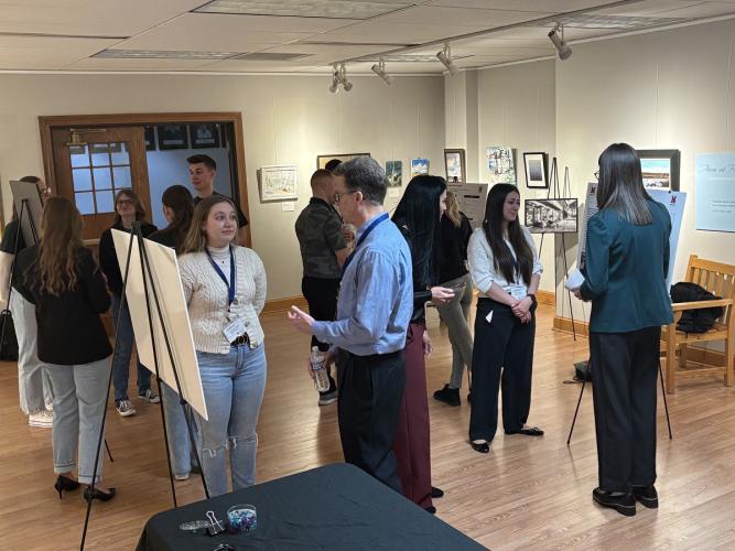 Students, faculty and staff look over the poster presentations at the AURCO Conference