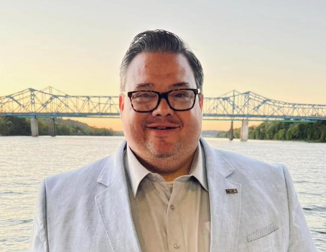 Portrait of man in suit jacket with glasses with bridge in background