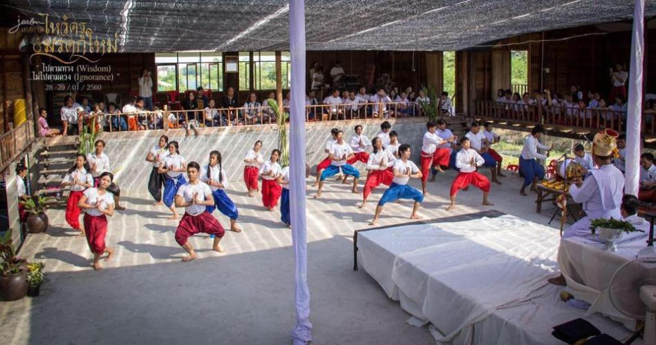 Thai Moradokmai Theatre dancers are shown dancing in a large group