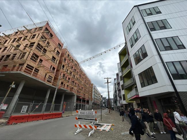 Two buildings with a street between them against a cloudy sky.
