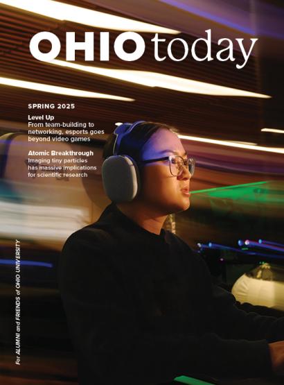 an asian woman wearing a black shirt, headphones and glasses stares off page, surrounded by blurred lights