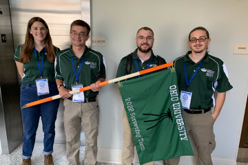 Liz Zimmer, Jonathan Beiter, Garrett Spargur, and Joe Cusimano pose with a surveying flag.