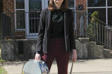 Casey Morarity stands with drum outside Glidden Hall