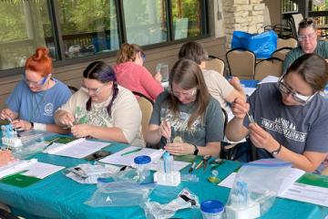 Science teachers extracting DNA from lettuce, carrots, tomatoes, and strawberries. The teachers are wearing goggles.