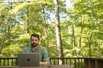 An OHIO student works on a computer while sitting outside