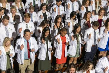 Graduates stand at HCOM white coat ceremony 2023