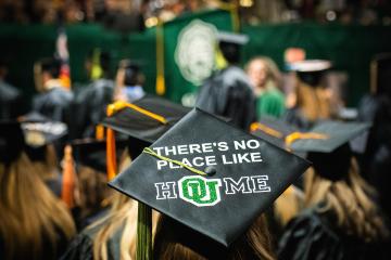 An OHIO's student is shown wearing a cap that says "There's No Place Like HOUME" at Commencement