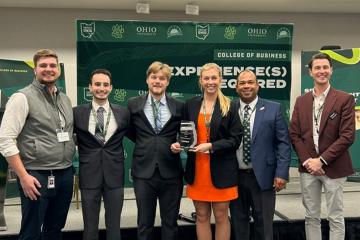 A group of people pose for a picture in a conference room, displaying a trophy