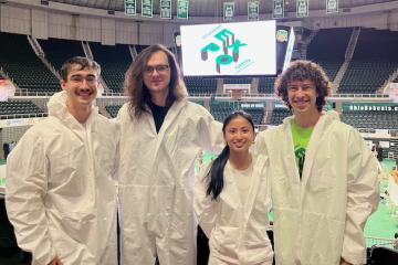 John Gilbert, Michael Cooney, Xiangsi Howard and Gabriel Havas stand in the Convocation Center during the Student Research Expo
