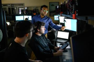 Three individuals look at computer screens in an OHIO classroom