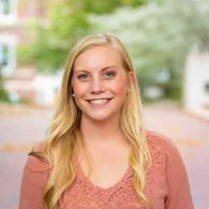 Paige McClain smiles at the camera wearing a pink blouse.