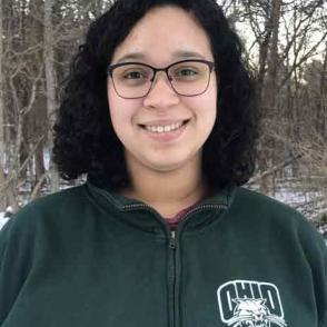 Shasta Kamara smiles and wears a dark green Ohio quarter zip hoodie