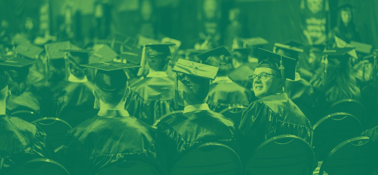 Students sit wearing their caps and gowns during Ohio University's Commencement ceremony