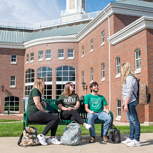 Students sit outside talking. 