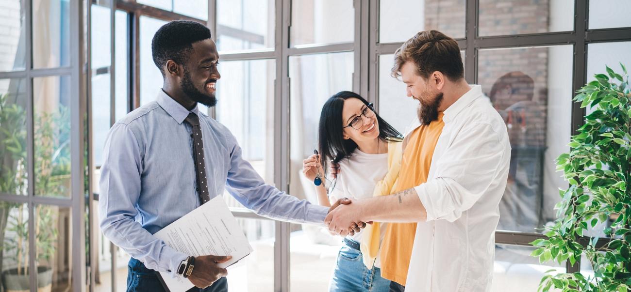 A real estate agent hands keys to homebuyers