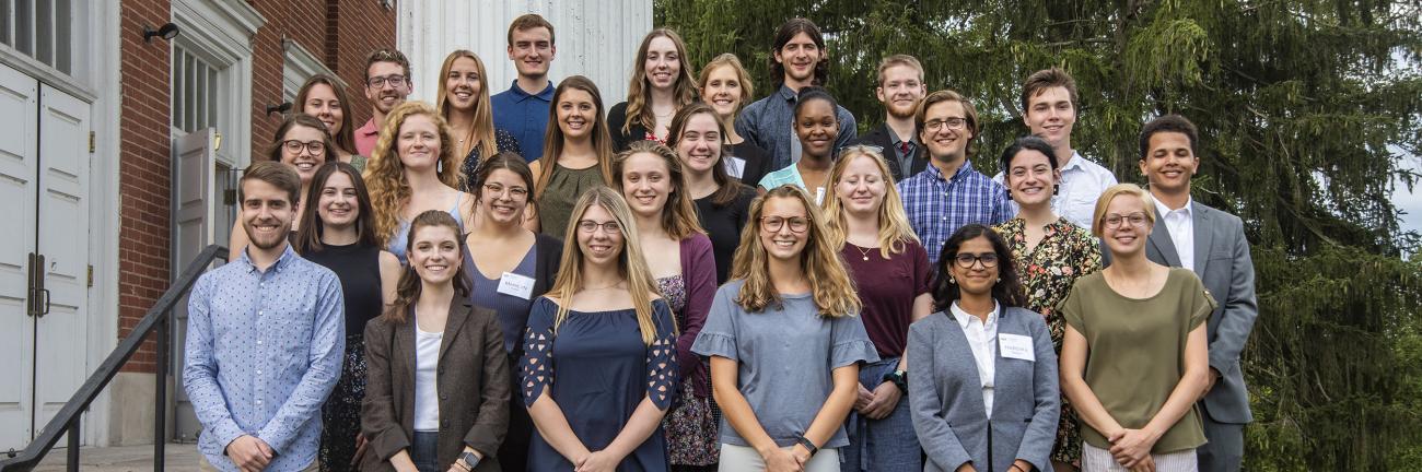 A group of 25 students standing together on steps. 