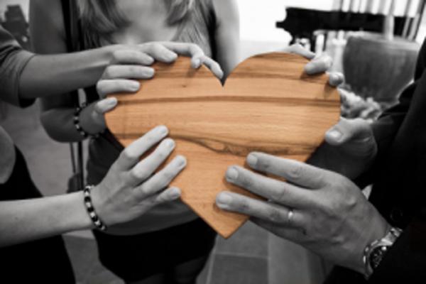 Hands holding on to a wooden heart