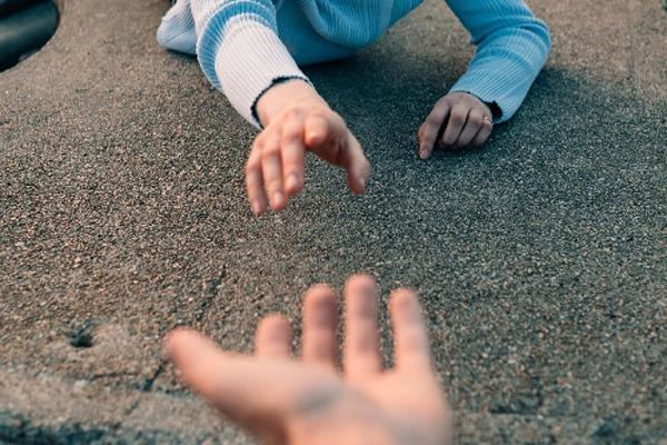 An adult hand reaching out to another set of hands 